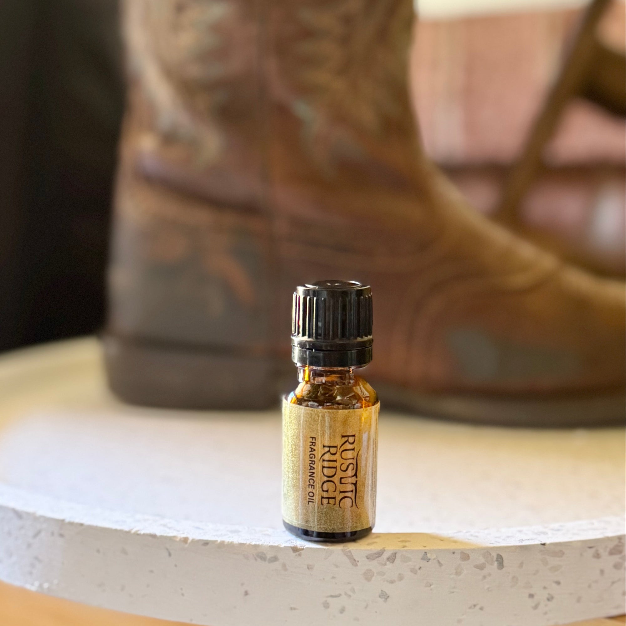 Small bottle of cologne on a wooden surface with a cowboy boot in the background