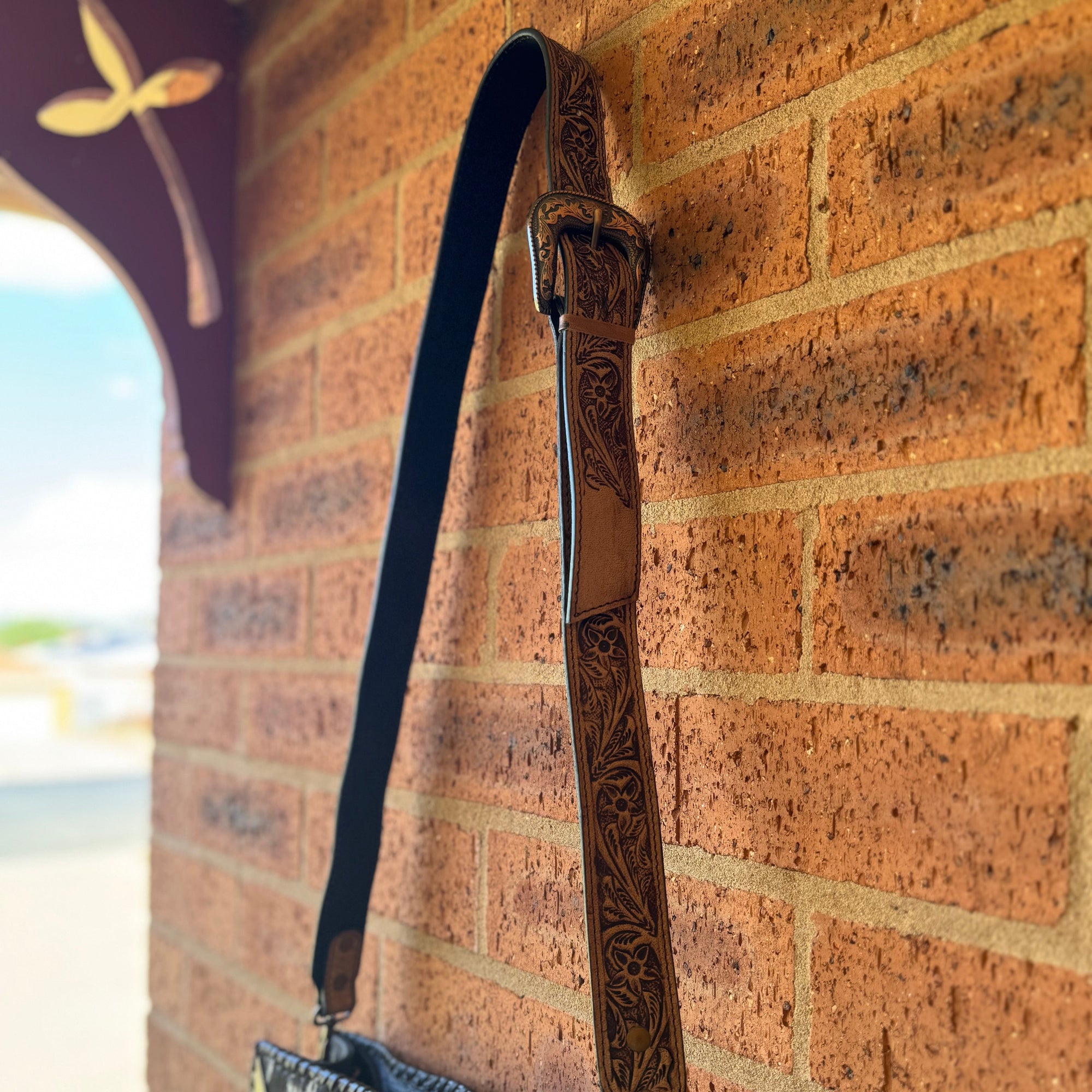 Handbag with a decorative strap against a brick wall