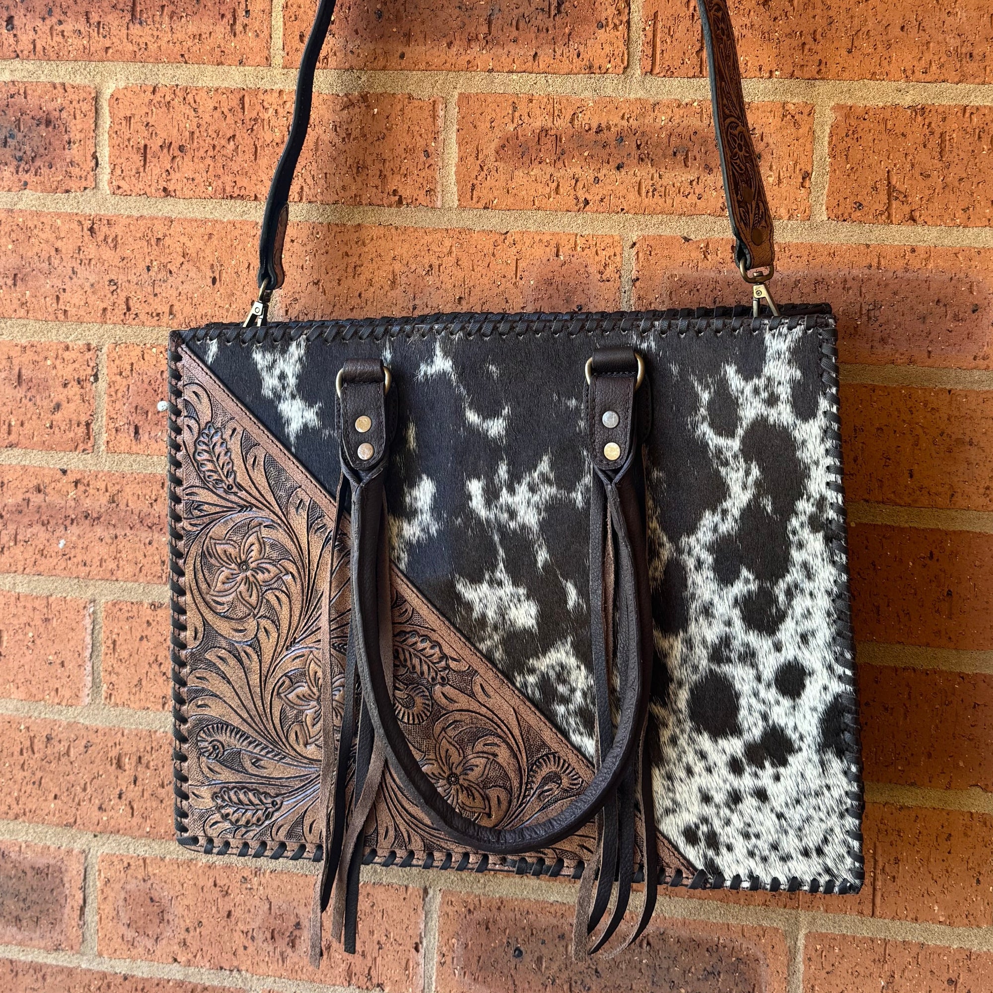 Handbag with black and white pattern against a brick wall