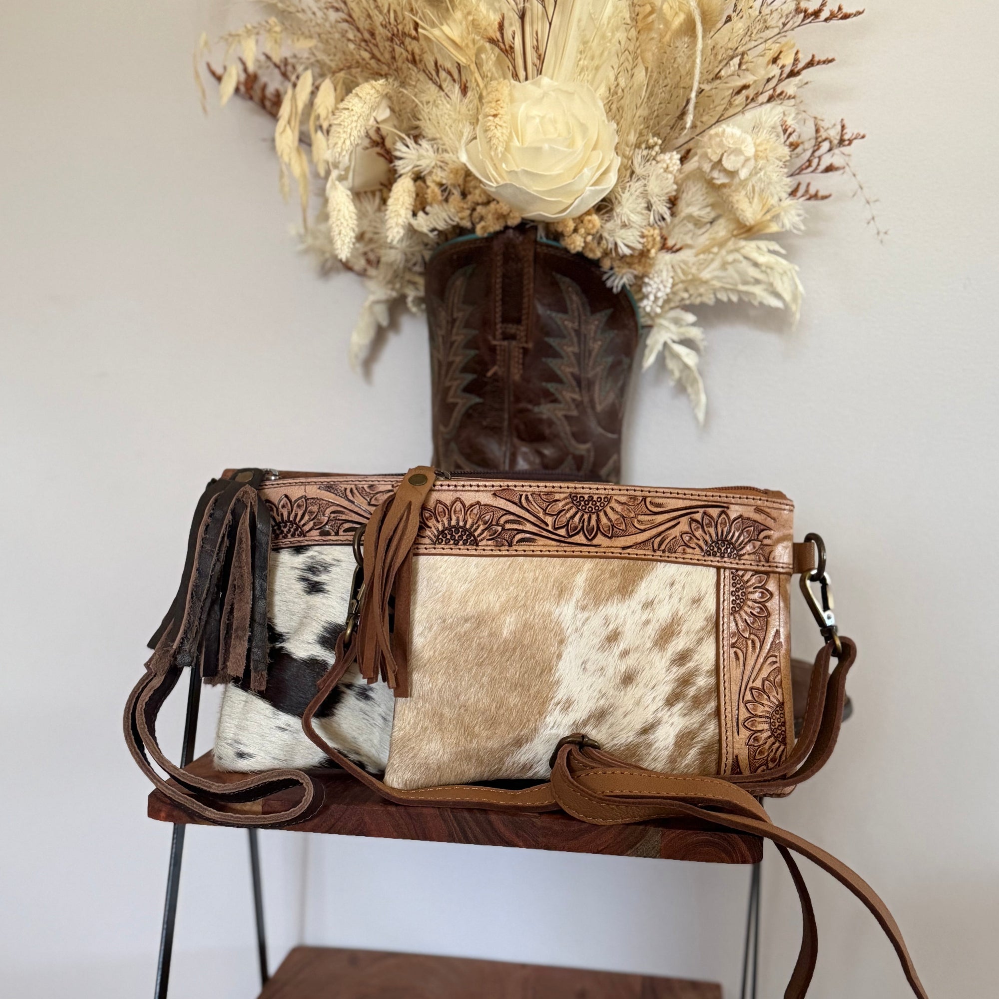 Brown leather handbag with cowhide pattern on a wooden shelf against a white wall.
