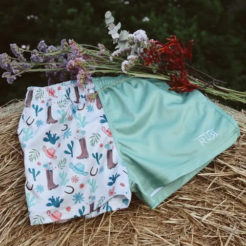 Two pairs of shorts on a hay bale with flowers in the background