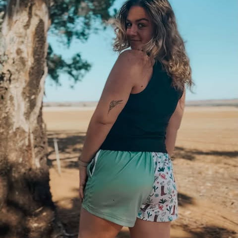 Woman standing outdoors near a tree with a desert landscape in the background