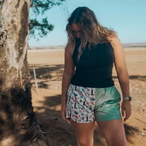 Woman standing under a tree in a desert-like setting