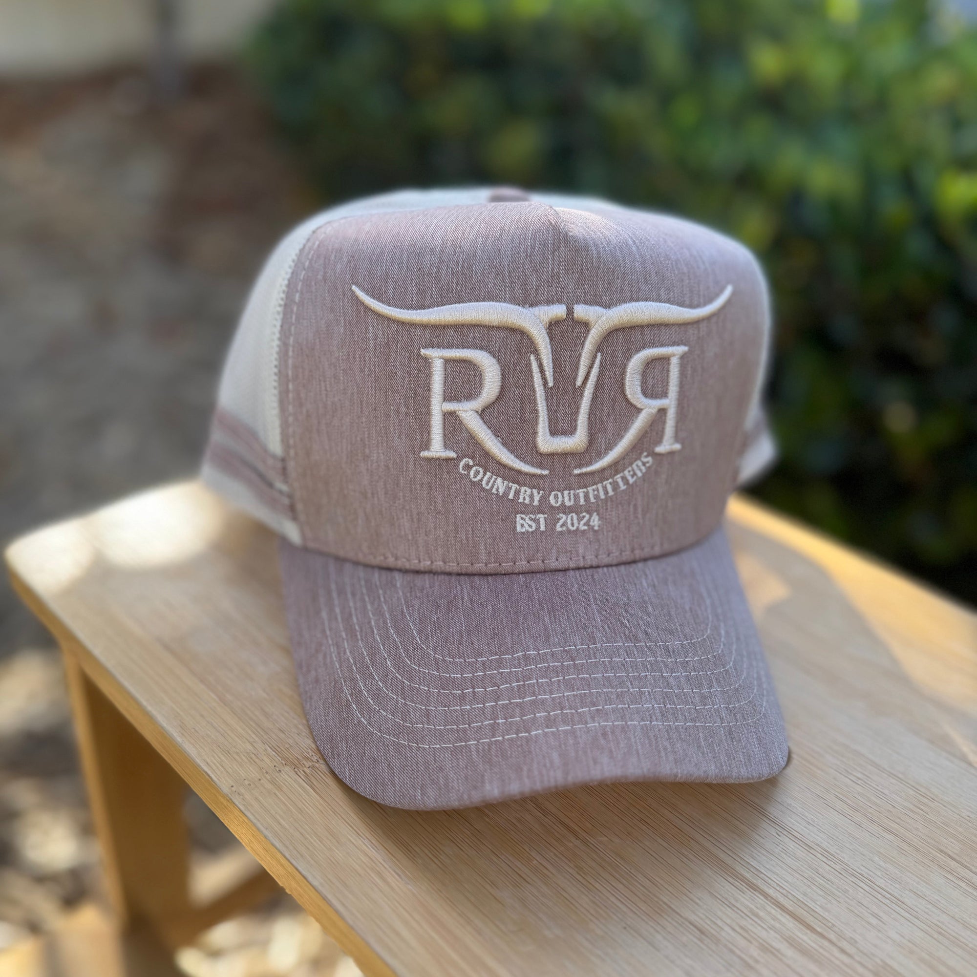 Trucker hat with 'RVR' logo on a wooden surface outdoors