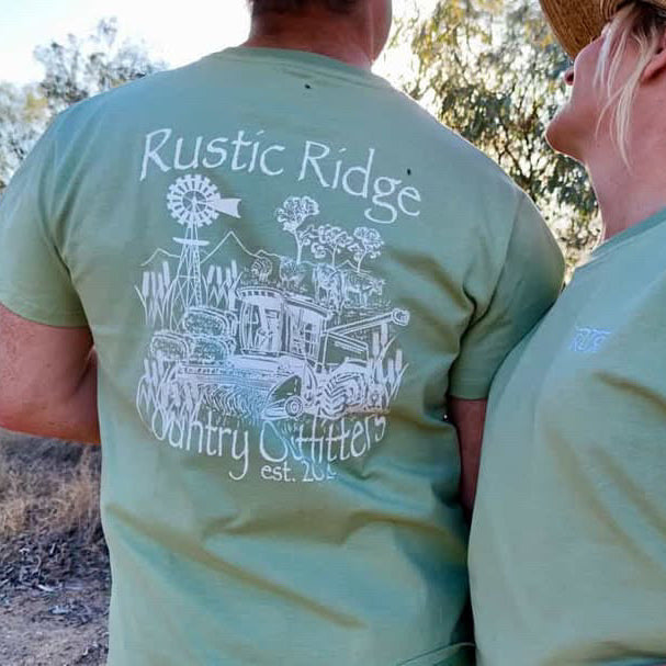 Two people wearing green t-shirts with 'Rustic Ridge Country Outfitters' design outdoors.