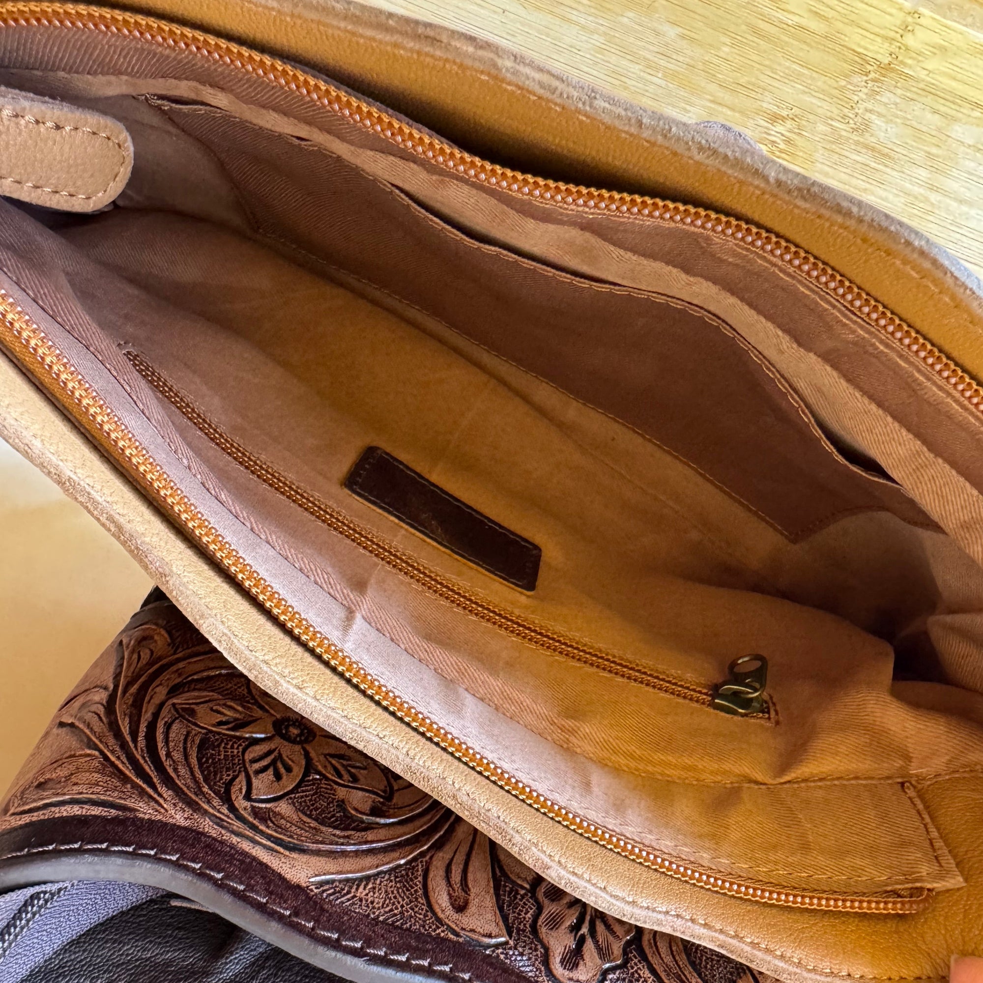 Close-up of a brown leather bag with intricate stitching on a white background
