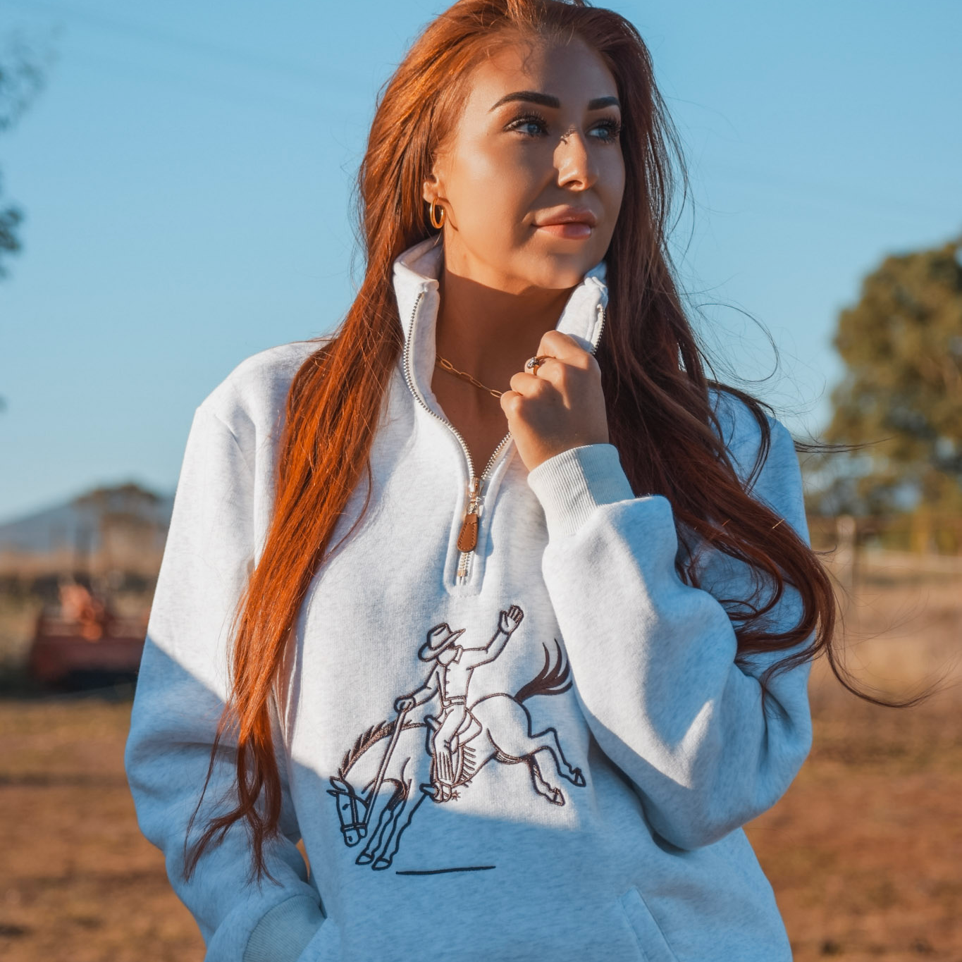 Woman wearing a light blue hoodie with a graphic design outdoors