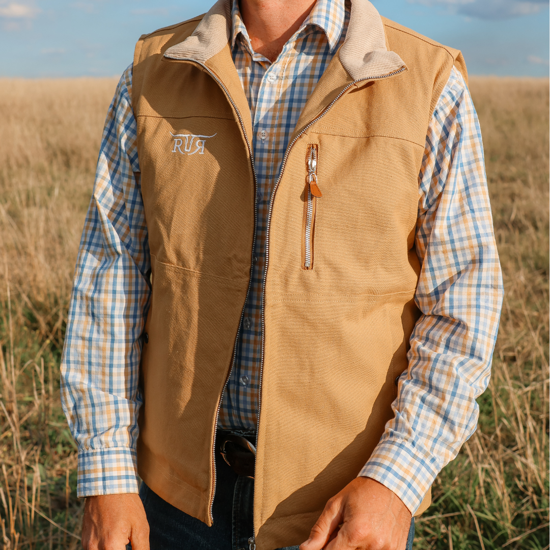 Person wearing a brown vest over a plaid shirt in an outdoor setting