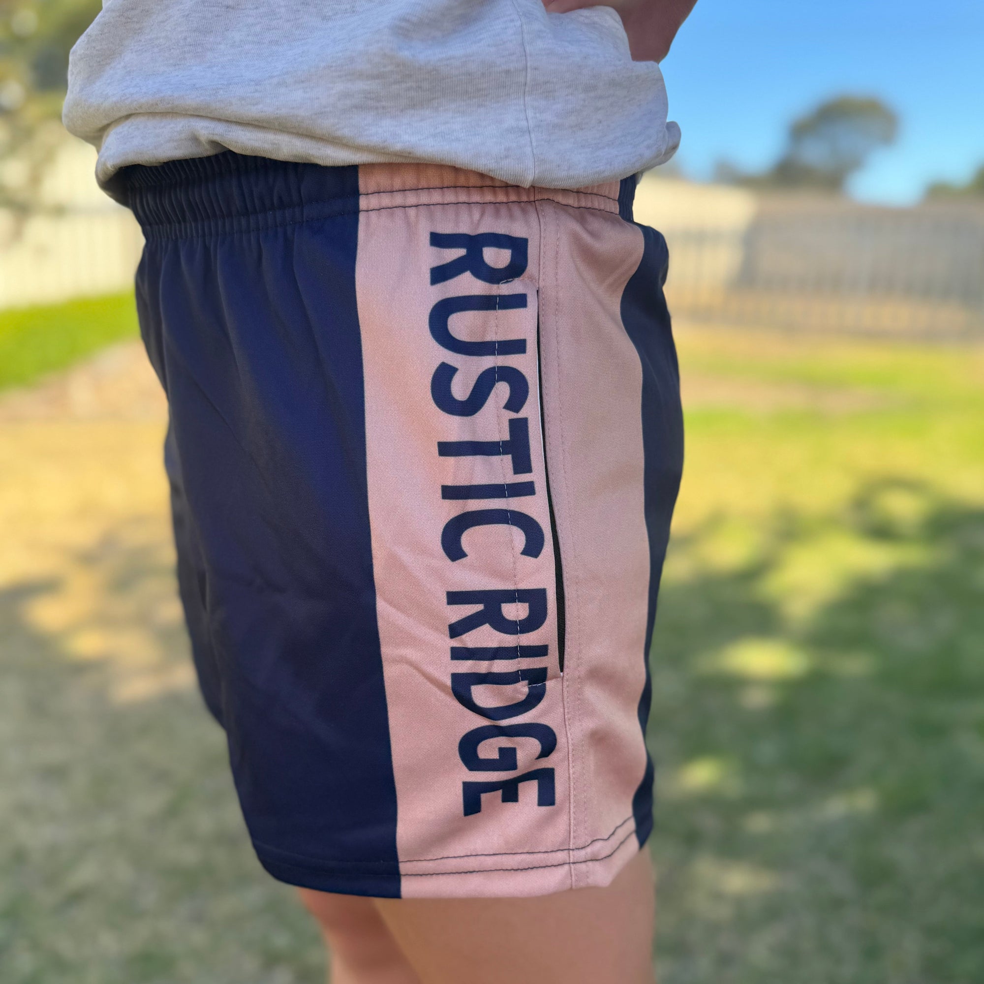 Person wearing shorts with 'Rustic Ridge' branding outdoors.