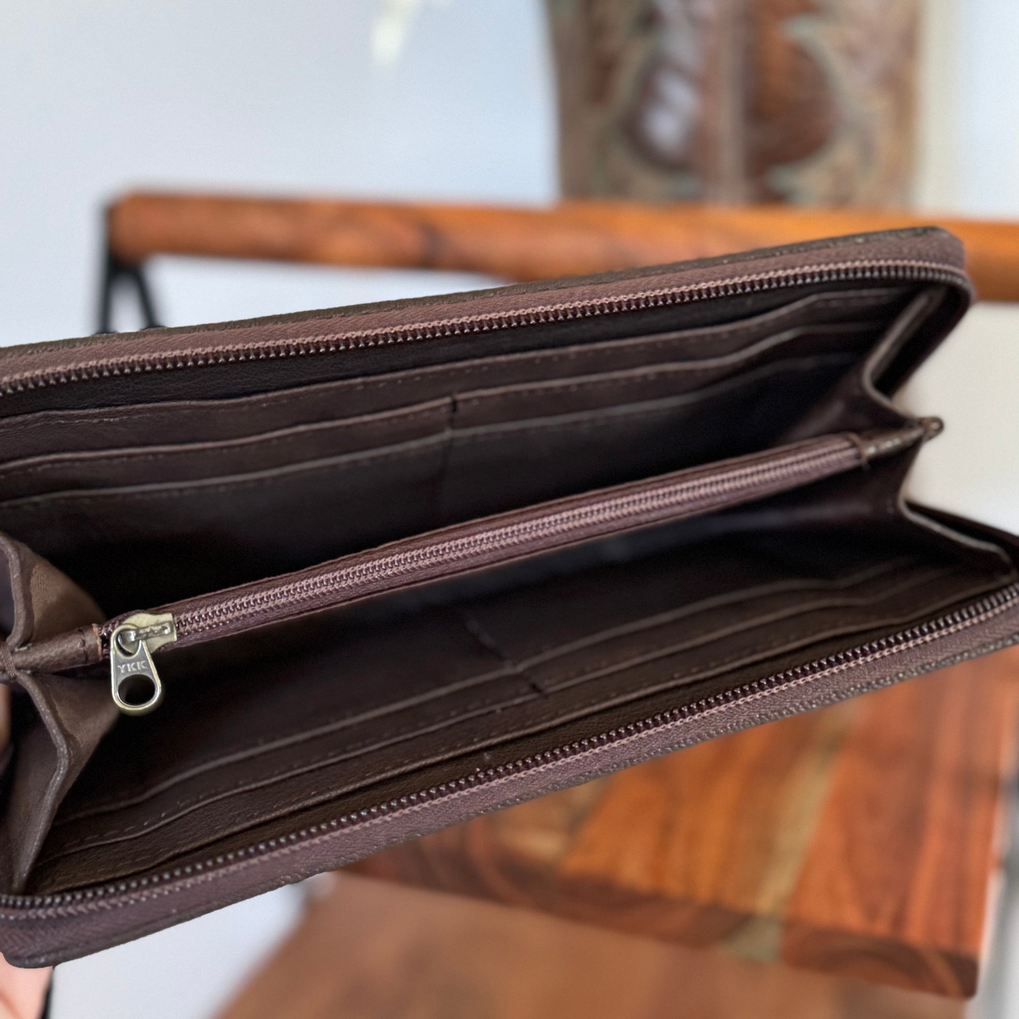 Brown leather wallet with a zipper on a wooden surface