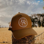 Brown hat with logo 'RR' on the front. Sitting on a cement post