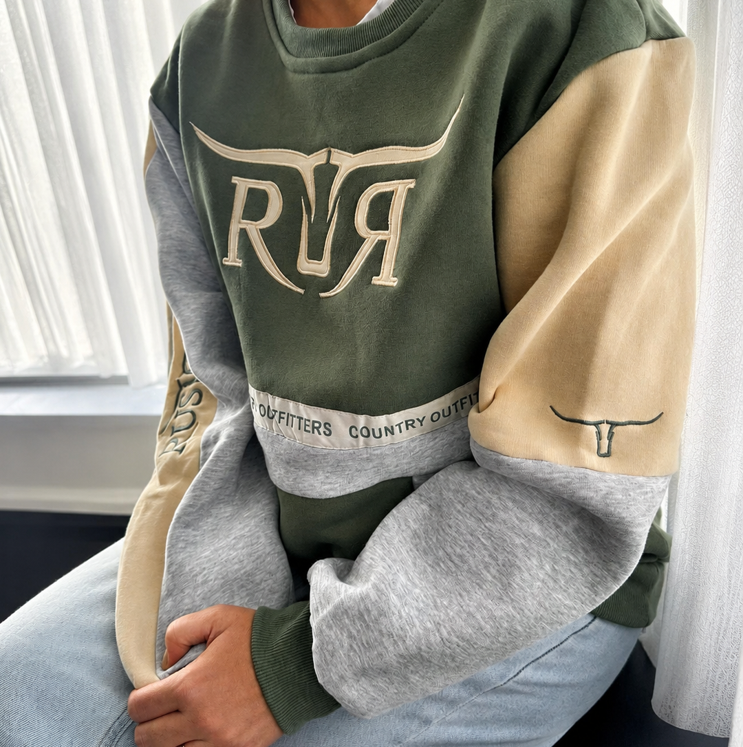 A person wearing a color-blocked sweatshirt with an olive green body, beige sleeves, and heather gray lower sleeves, featuring a large cream 'RR' graphic on the chest and a matching  longhorn outline on the right sleeve.
