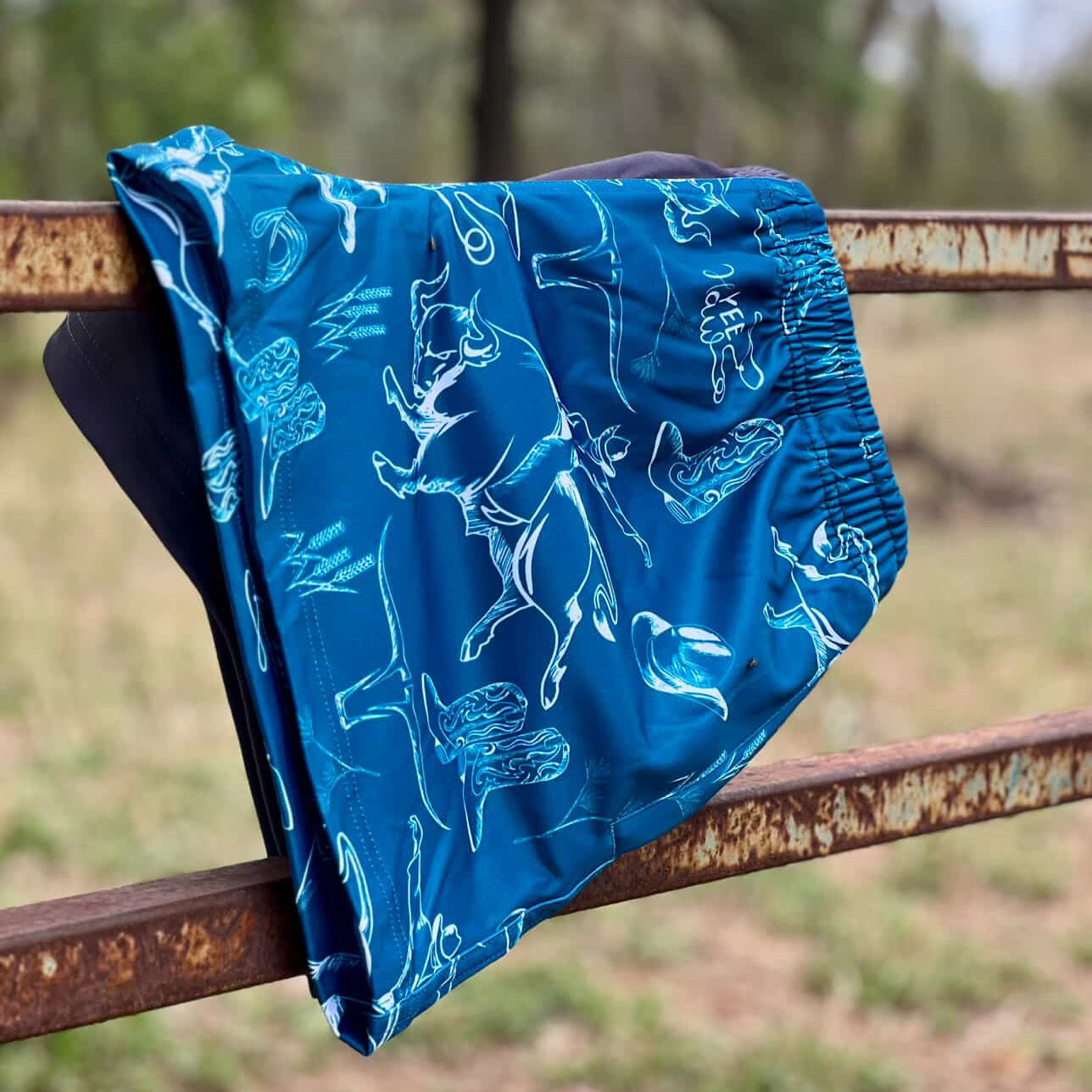 Blue patterned fabric draped over a rusty metal bar with a natural background