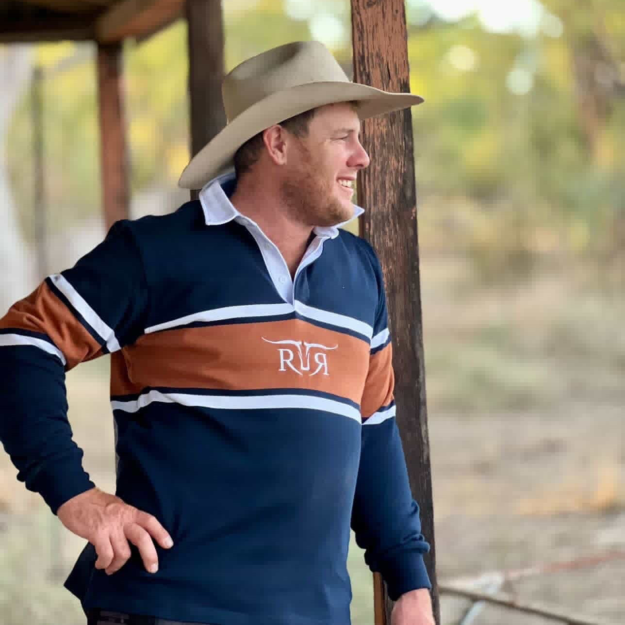 Man wearing a striped rugby shirt with 'RR' logo on a wooden structure.