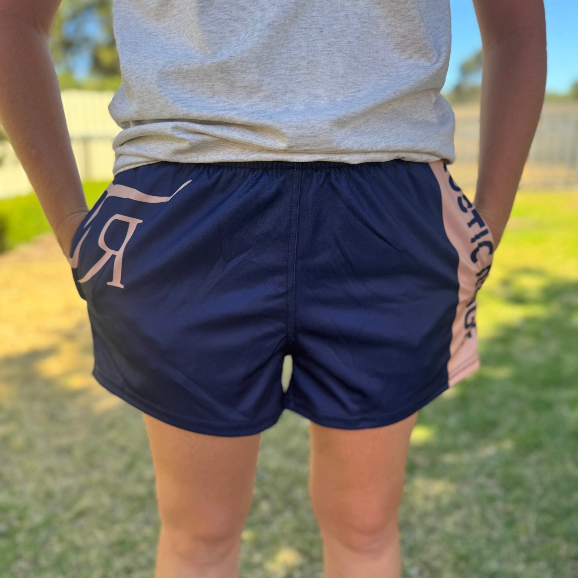 Person wearing navy shorts with a logo on a grassy background