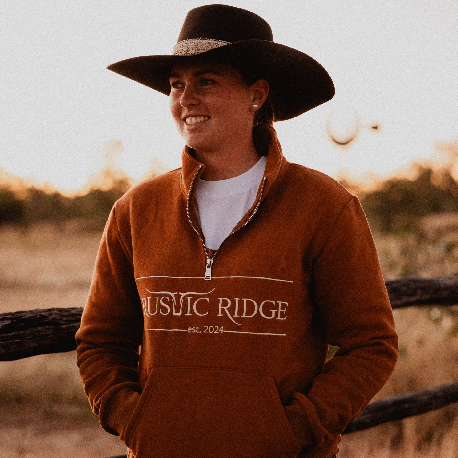 Person wearing a brown sweatshirt with 'Rustic Ridge' text, standing in a field.