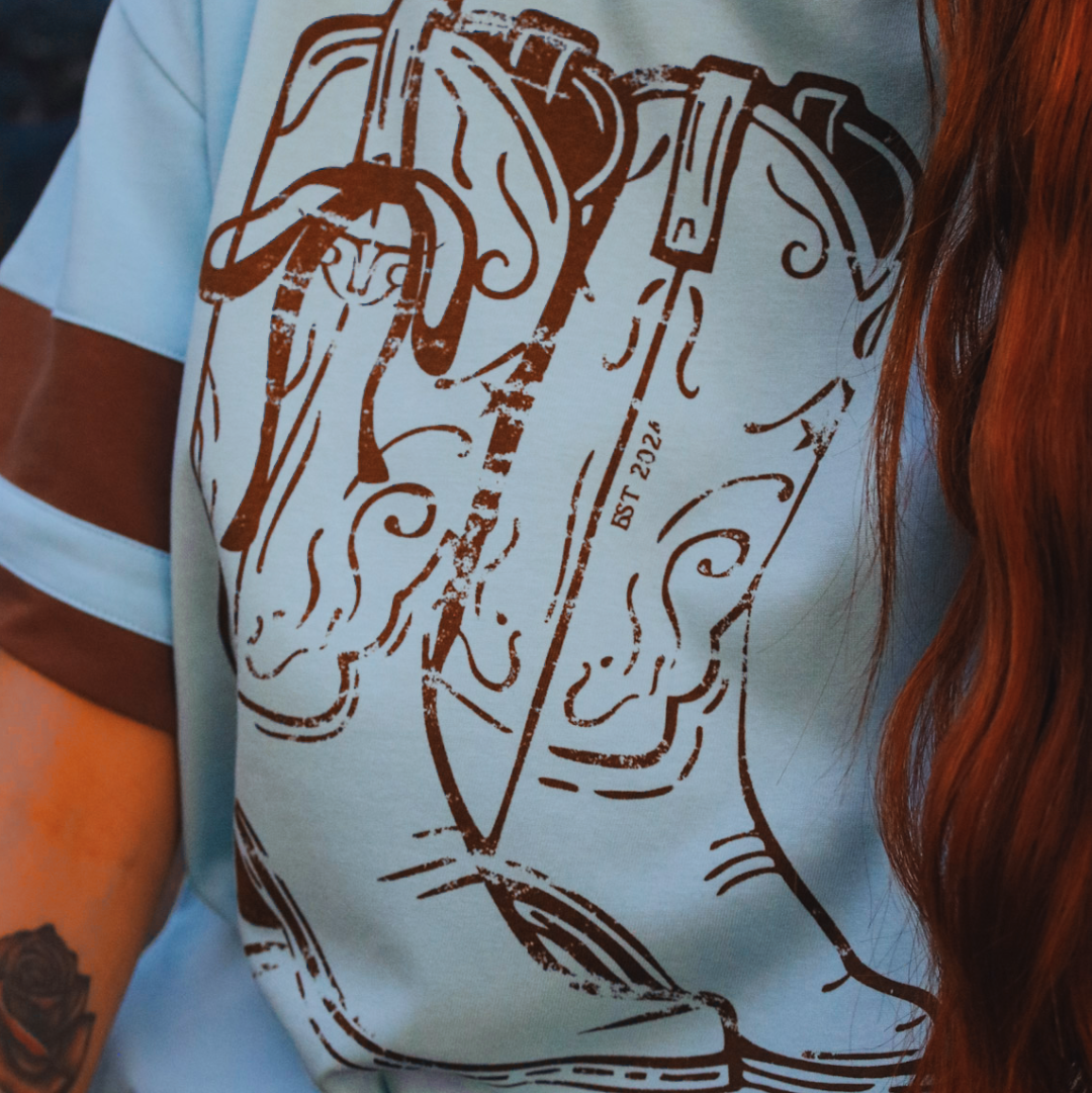 Person wearing a shirt with a brown graphic design of a horse and saddle.