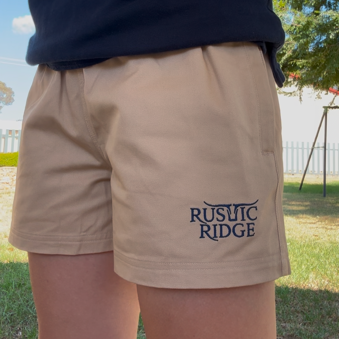 Person wearing beige shorts with 'Rustic Ridge' branding outdoors.
