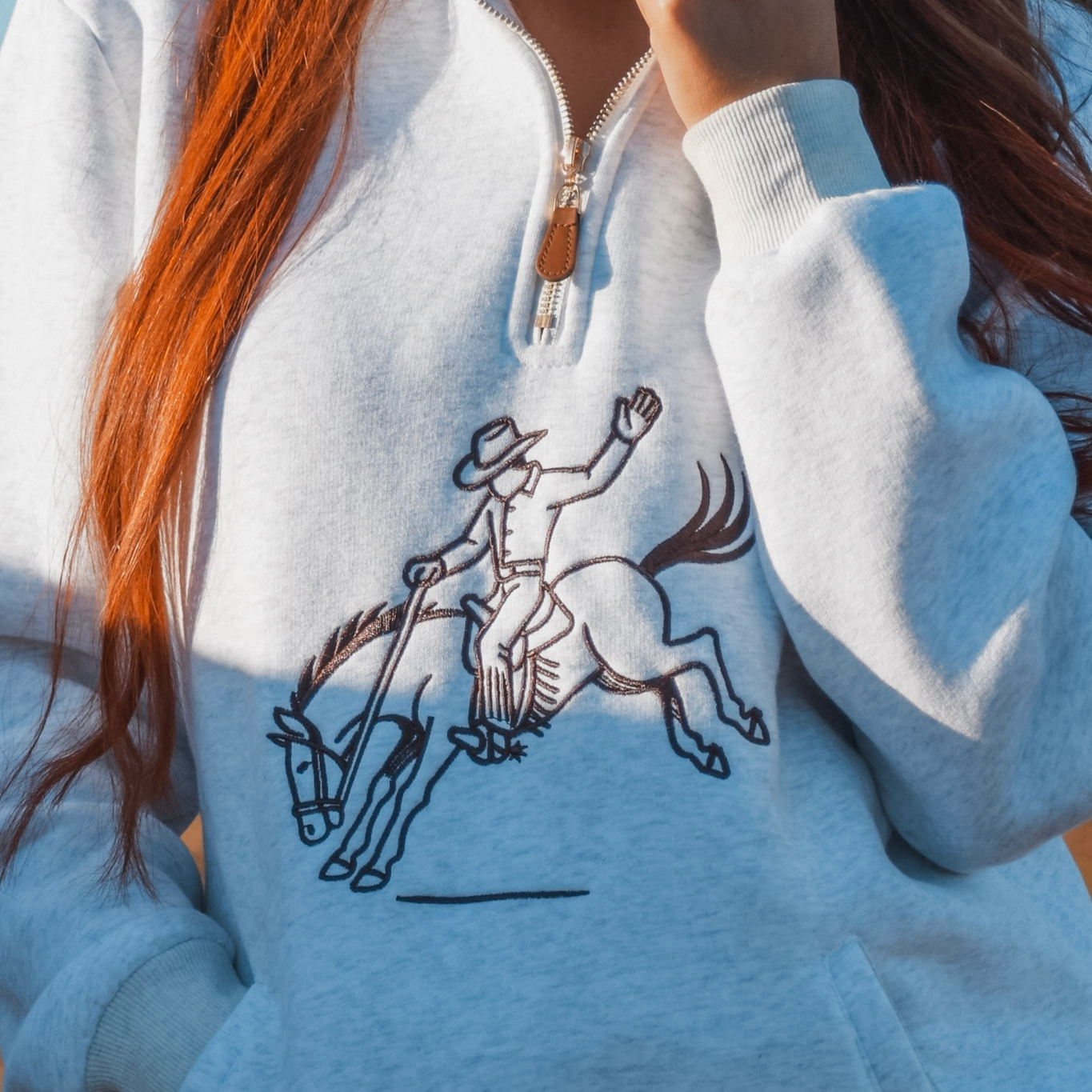 Person wearing a light blue hoodie with a graphic design of a person on horseback.