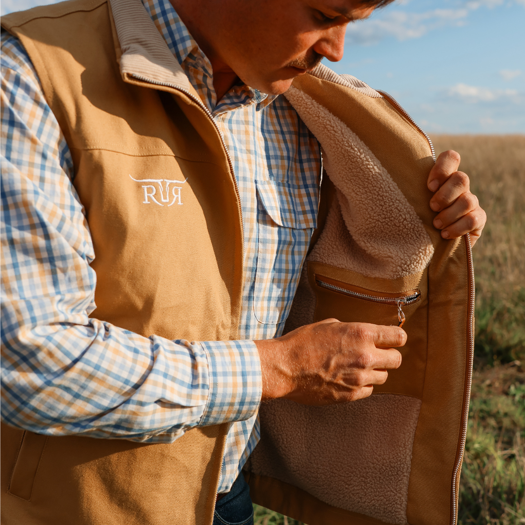 Man wearing a brown vest with a visible brand logo, outdoors.