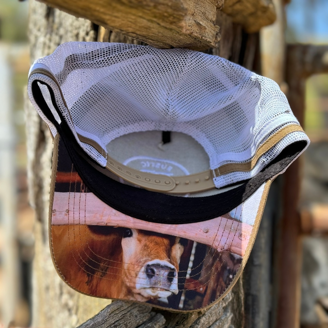 Trucker cap with a cow under the brim sitting on a wooden post