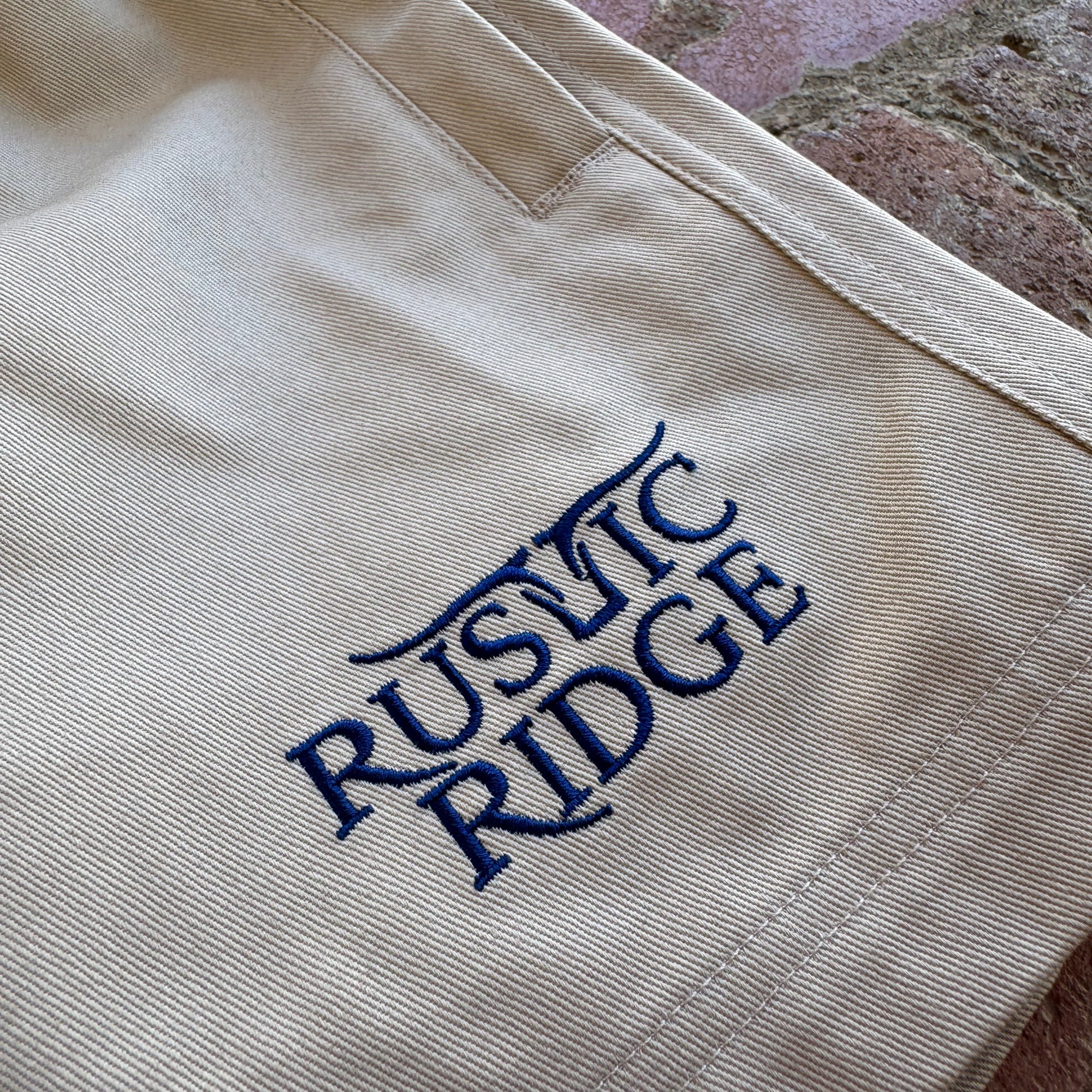 Beige fabric with blue embroidered text on a textured surface