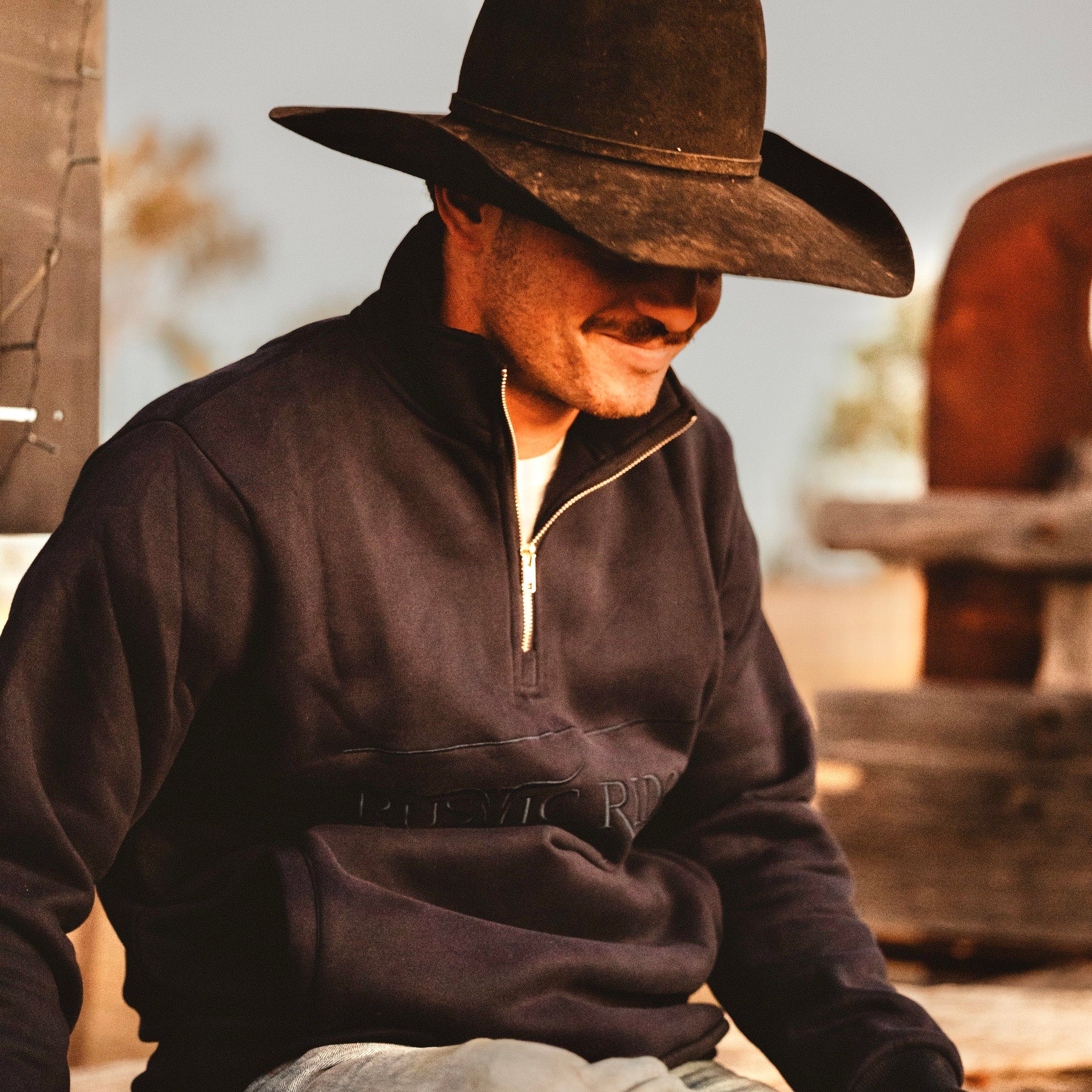 Man wearing a dark jacket and cowboy hat in an outdoor setting