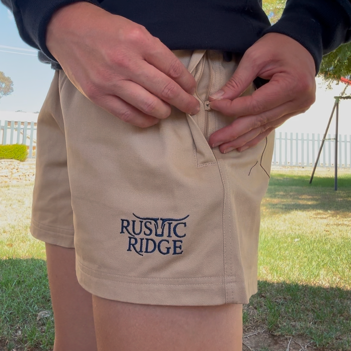 Person wearing a brown and navy sweater with beige shorts featuring 'Rustic Ridge' branding.